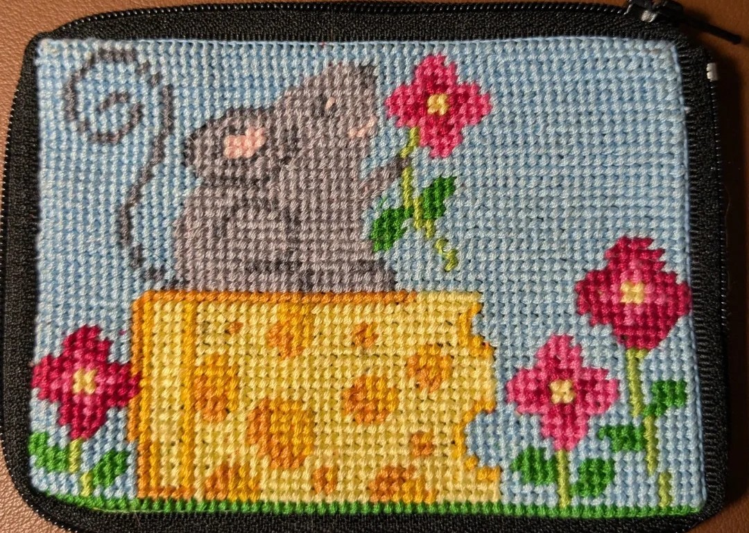 needlepoint: a mouse sitting on cheese holding a flower